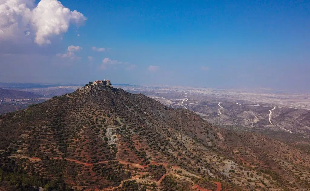 Photo of the tall peak of Mount Stavrovuni with the Stavrovouni Monastery at the top and the landscape for miles behind the mountain, Cyprus
