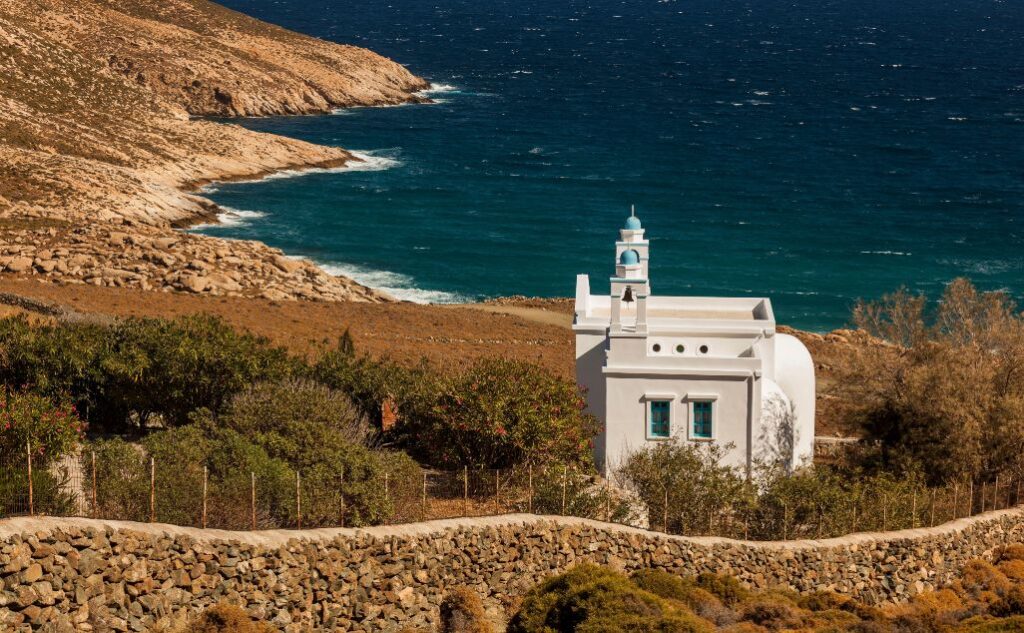 Picture of a Tiny white church in Tinos with the sea behind it
