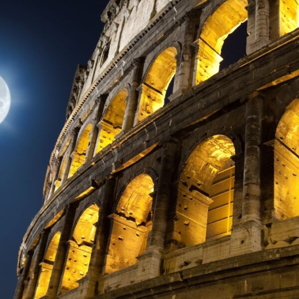 colosseum at night, lit up inside and with a full moon everhead
