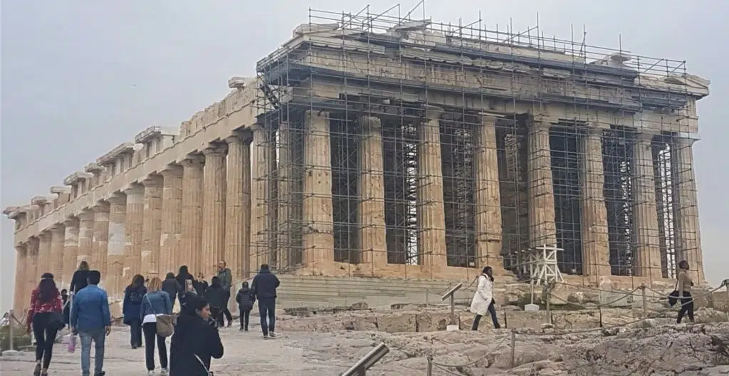 Photo of the side and front of the Parthenon with the front covered in scaffolding on a grey early evening at the Acropolis of Athens, Greece